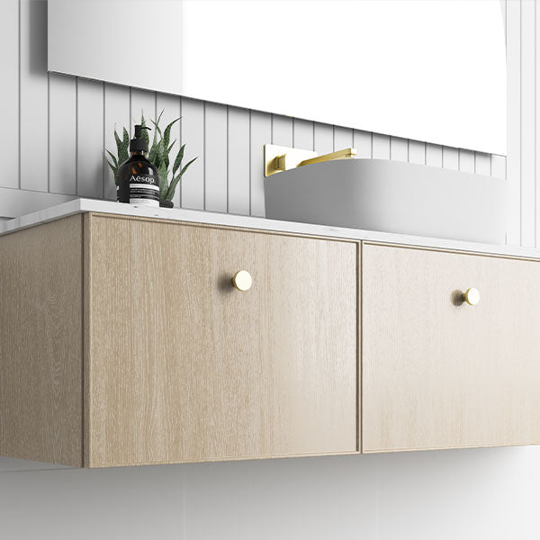 Marquis Chifley wall hung vanity in light woodgrain finish, with round brass knobs and above-counter basin in a bathroom setting