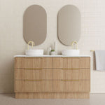 Marquis Lake floor standing vanity in Coastal Oak with white top, double basins and brass handles in bathroom setting