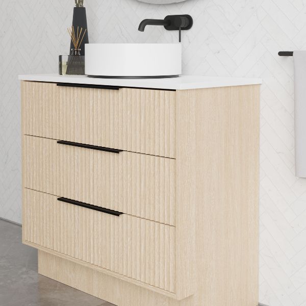 Marquis Lake floor standing vanity in coastal oak with white top and black handles, shown with round above-counter basin