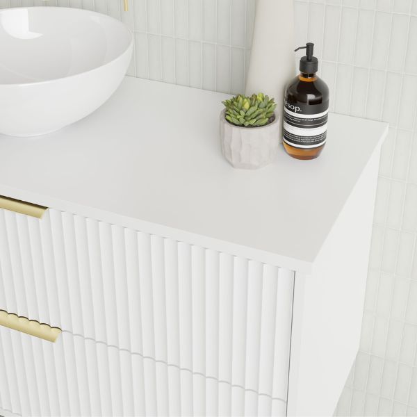 Marquis Lake wall hung vanity with white benchtop, ribbed front panels and brass handles, styled with basin, soap dispenser and plant