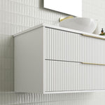 Marquis Lake wall hung vanity in white with fluted drawers, brass handles and above-counter basin, angled view