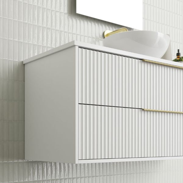 Marquis Lake wall hung vanity in white with fluted drawers, brass handles and above-counter basin, angled view