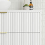 Marquis Lake wall hung vanity with white fluted drawers, brushed brass handles and white benchtop, close-up in bathroom