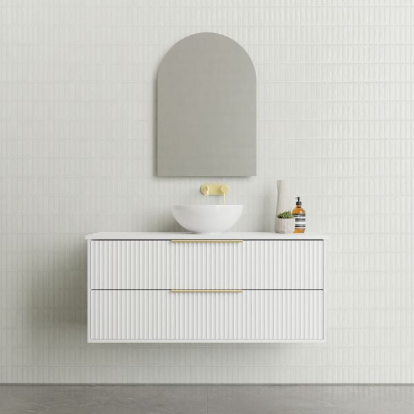 Marquis Lake wall hung vanity in white with fluted drawers, brass handles and round above-counter basin beneath an arched mirror