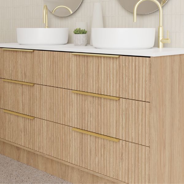 Marquis Lake floor standing vanity in coastal oak with white top, two basins and gold handles in a bathroom setting