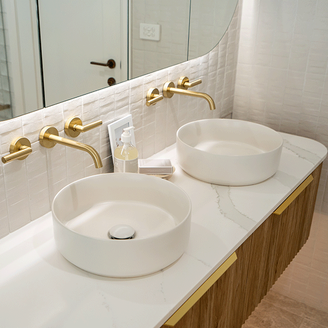 Phoenix Vivid Slimline Plus brushed gold wall top assemblies with lever handles above twin bathroom basins