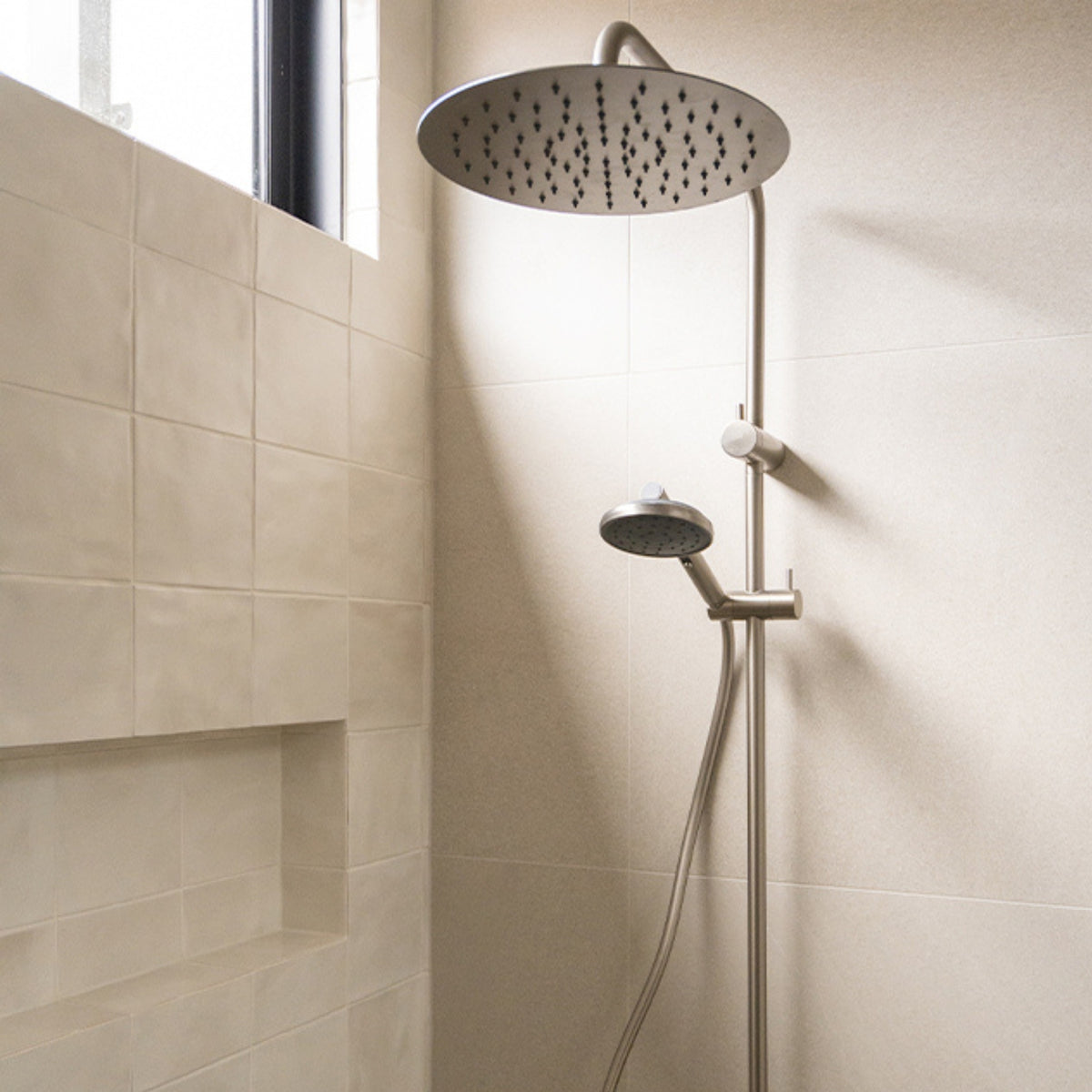 Caroma Urbane II brushed nickel twin rail shower with round overhead and hand shower in a tiled bathroom