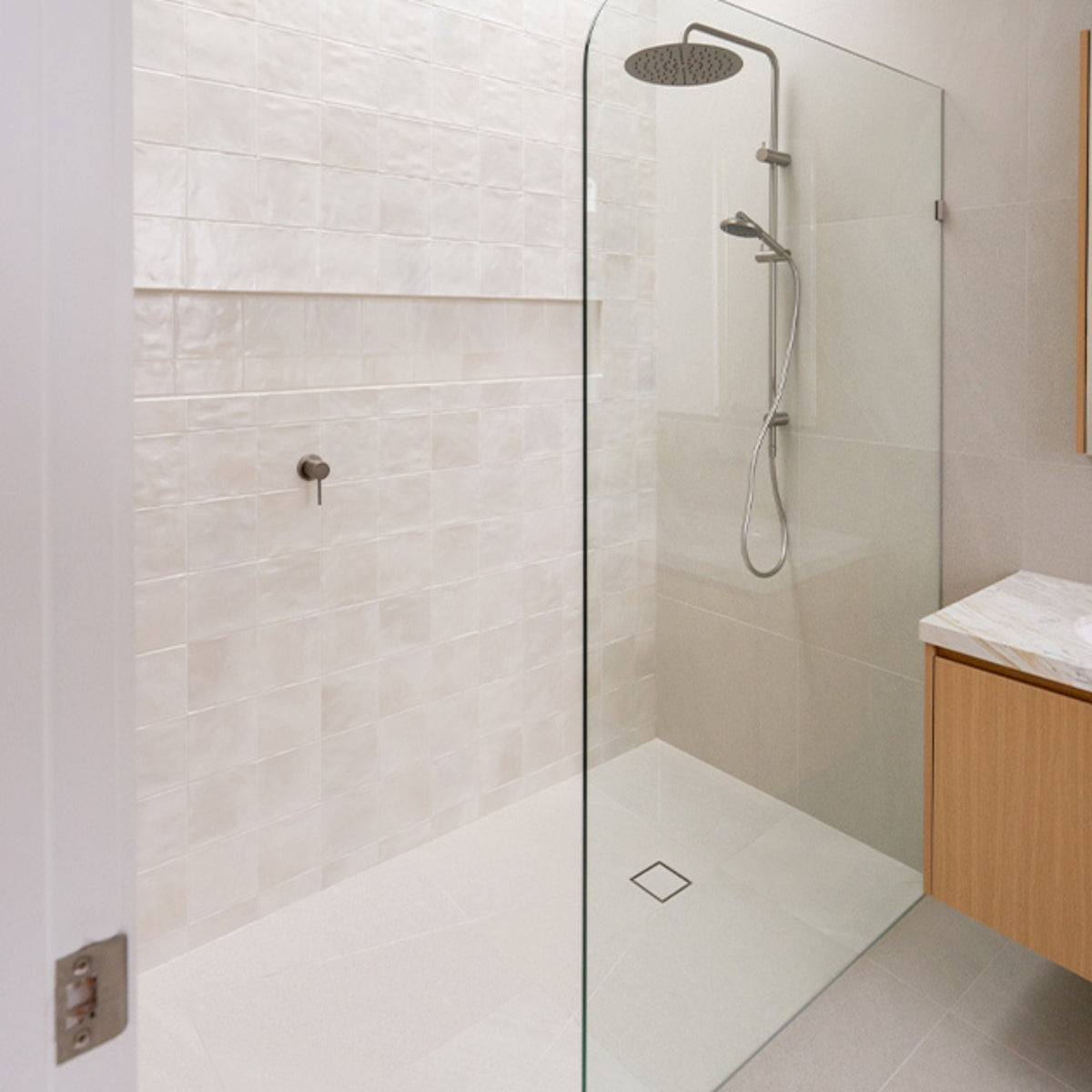 Caroma Urbane II brushed nickel twin rail shower in a modern bathroom, with round overhead rain shower and handheld spray.