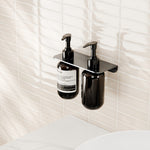 Nero Mecca double soap bottle holder in gun metal, wall-mounted with two pump bottles in a modern bathroom setting