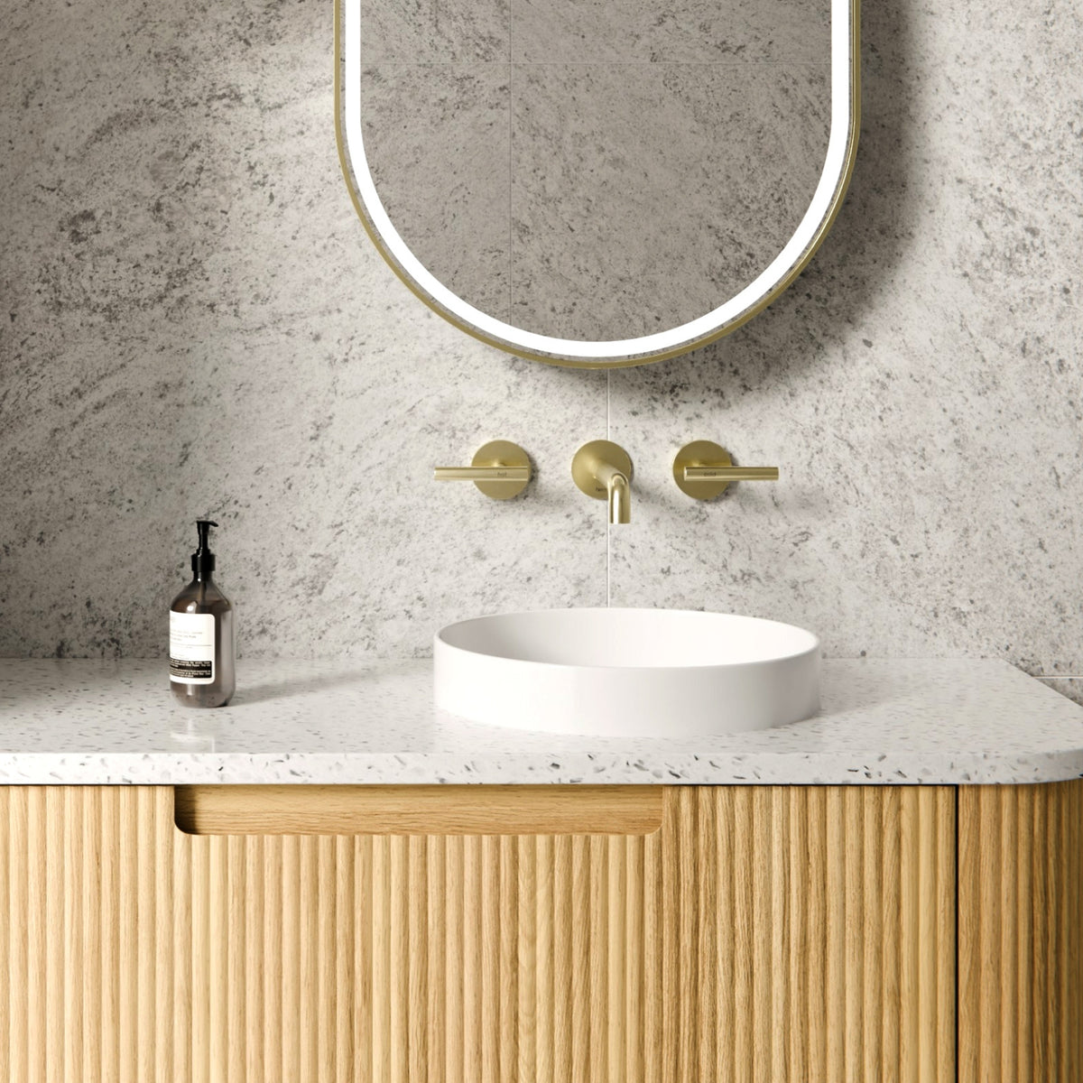 Nero Mecca brushed gold wall basin/bath set with 185mm spout and lever handles above a white round basin in a bathroom vanity