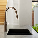 Nero Mecca Smart Sensor pull out kitchen mixer in brushed bronze, hob mounted over a black sink on a stone benchtop