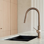 Nero Mecca pull out kitchen mixer in brushed bronze, shown mounted on a marble-look benchtop with black sink in kitchen setting