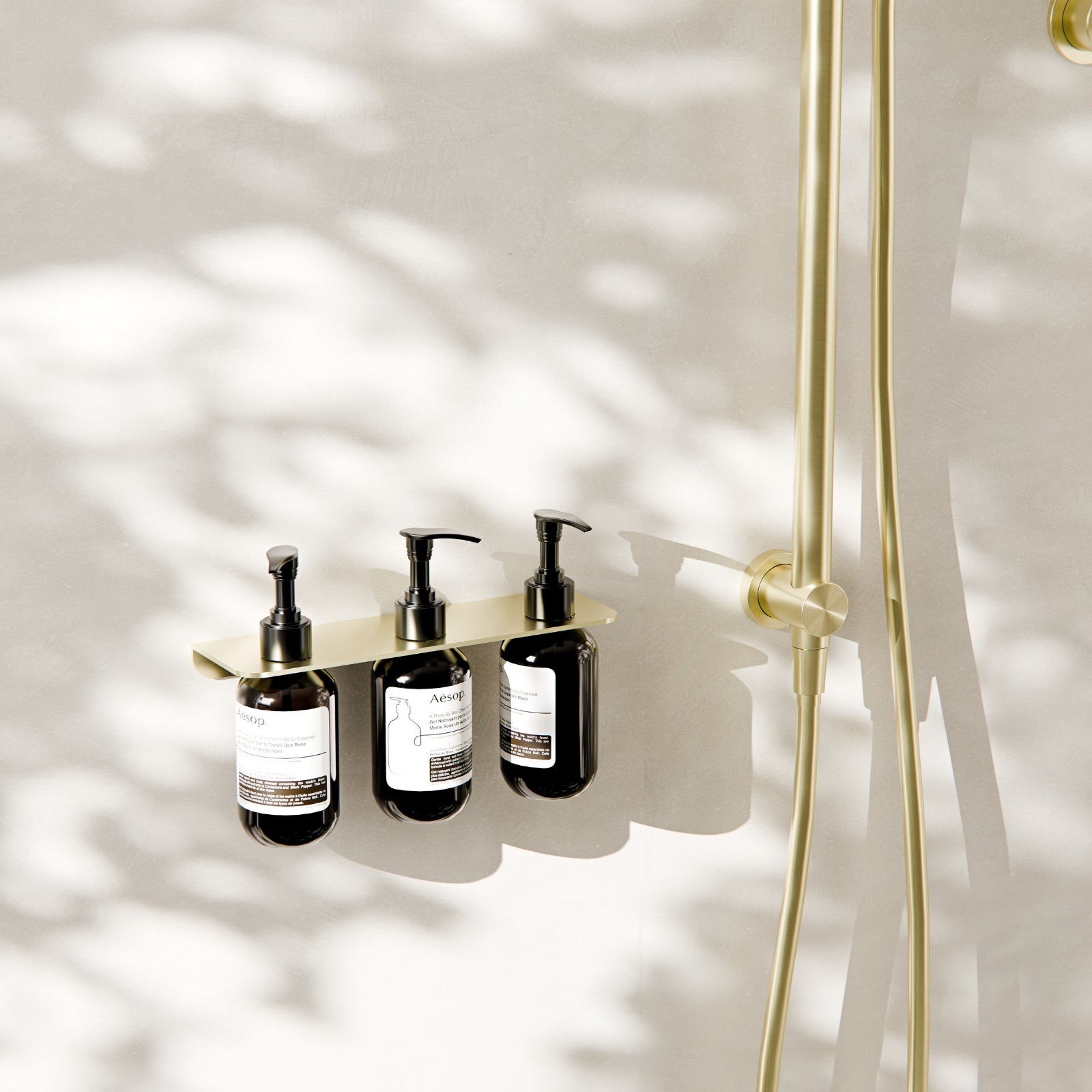 Nero Mecca triple soap bottle holder in brushed gold, wall-mounted with three pump bottles in a shower setting