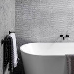 Nero Mecca matte black wall basin/bath mixer in a bathroom, shown above a freestanding bath with separate back plate