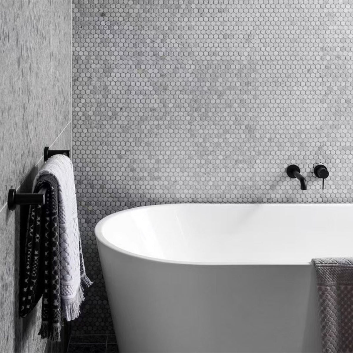 Nero Mecca matte black wall basin/bath mixer in a bathroom, shown above a freestanding bath with separate back plate
