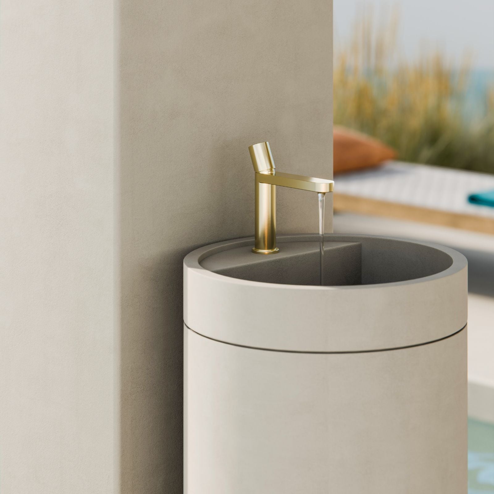 Nero Pure basin mixer in brushed gold, shown on a round stone basin in a bathroom setting