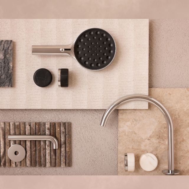 Nero Serenity brushed nickel shower system with Marquina black handle, hand shower and wall mixer components arranged on stone tiles