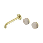 Nero Serenity wall basin set in brushed gold with 185mm offset spout and two travertine handles, wall-mounted on white background