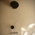 Nero Serenity wall shower head in brushed nickel, wall mounted in bathroom with round head and matching controls below