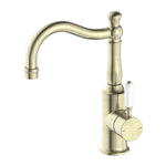 Nero York basin mixer tap in aged brass with hook spout and white porcelain lever, front view on white background