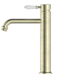 Nero York tall basin mixer tap in aged brass with white porcelain lever, side view on white background