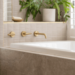 Caroma Newbury white rectangular island bath inset in a tiled hob, with brass wall mixer and warm bathroom setting