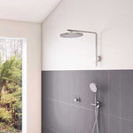 Phoenix NX IKO round chrome shower head and wall arm in a modern bathroom setting