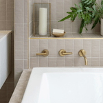 Caroma Newbury island bath in white acrylic, inset in tiled hob with brushed brass taps and shelf styling