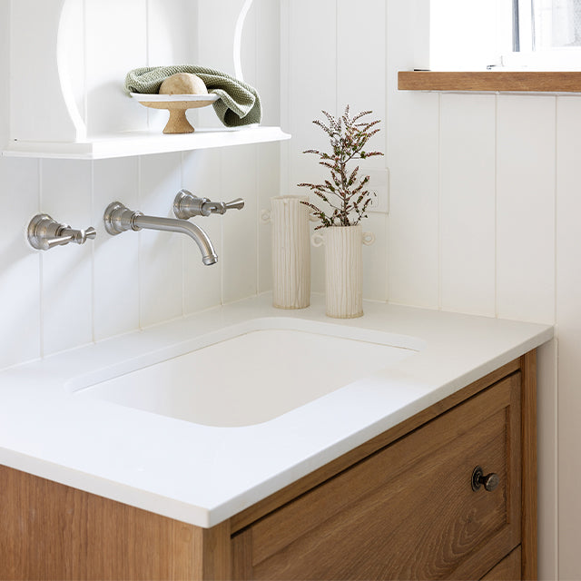 Phoenix Cromford brushed nickel wall basin/bath tap set with spout, shown installed over a vanity sink