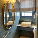 Phoenix Cromford double towel rail in brushed gold, mounted on a blue bathroom wall beside a vanity and mirror