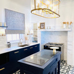 Brushed gold Phoenix Cromford exposed sink set on a kitchen sink with navy cabinetry and white tiled splashback
