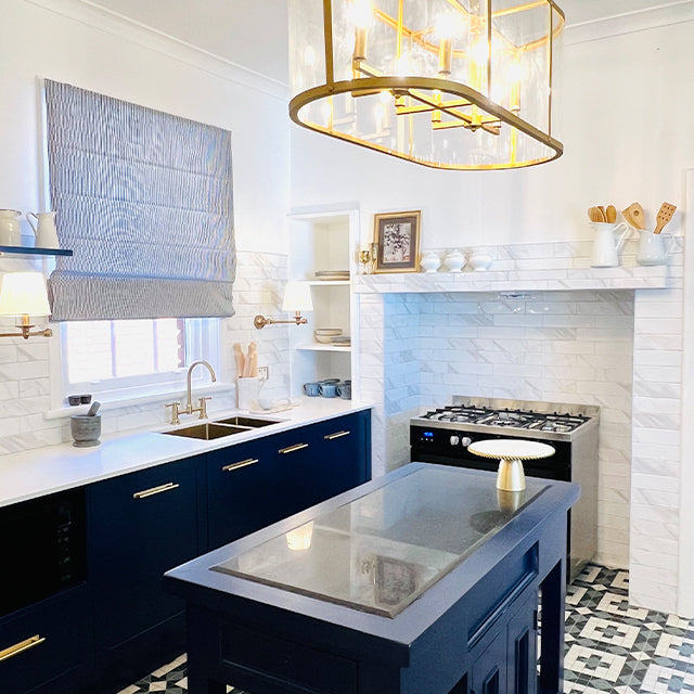 Brushed gold Phoenix Cromford exposed sink set on a kitchen sink with navy cabinetry and white tiled splashback