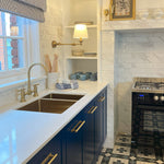 Phoenix Cromford brushed gold kitchen sink tap set with curved swivel spout and twin handles, installed beside a white sink