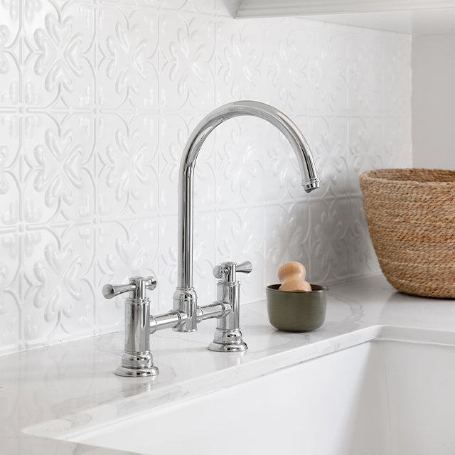 Phoenix Cromford exposed sink set in chrome on a white benchtop with gooseneck swivel spout and twin handles