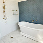 Phoenix Cromford glass shelf 450mm brushed gold, wall-mounted above bath in bathroom setting