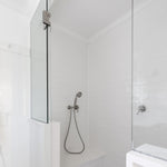 Phoenix Cromford brushed nickel wall shower mixer on a white tiled shower wall, with handheld shower fitting visible