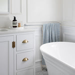 Phoenix Cromford chrome single towel rail mounted on a white bathroom wall beside a bath, holding a blue towel