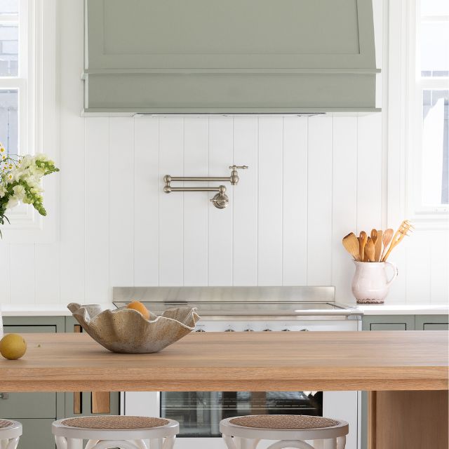 Phoenix Cromford wall mounted pot filler in brushed nickel, shown folded against a white kitchen splashback above a cooktop