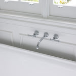 Phoenix Cromford chrome wall top assemblies with extended spindles, mounted above a bath in a bright bathroom view