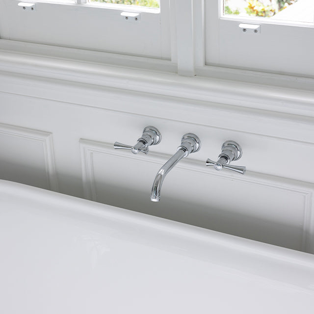 Phoenix Cromford chrome wall top assemblies with extended spindles, mounted above a bath in a bright bathroom view