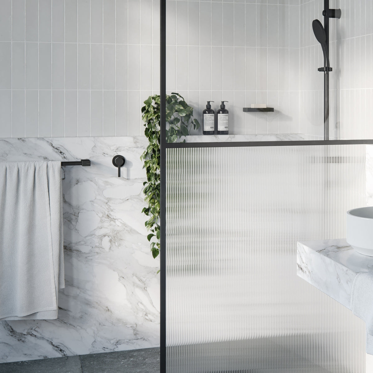 Modern bathroom showing matte black wall mixer, shower rail, towel rail and round lever tap with marble-look tiles