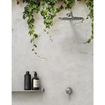 Phoenix Vivid Slimline stainless steel wall mixer and shower head in an outdoor shower setting, with slim lever and round wall plate