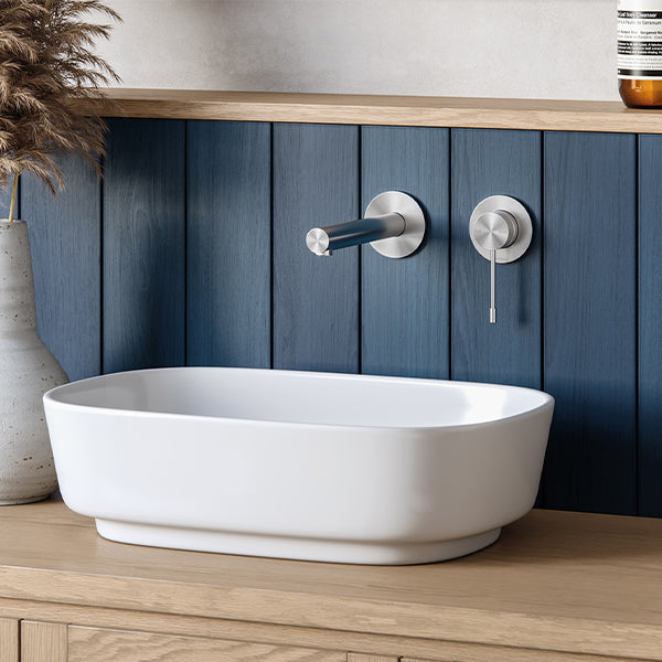 Phoenix Vivid Slimline wall bath mixer set in stainless steel, shown with round wall plates over a white bath in a bathroom setting