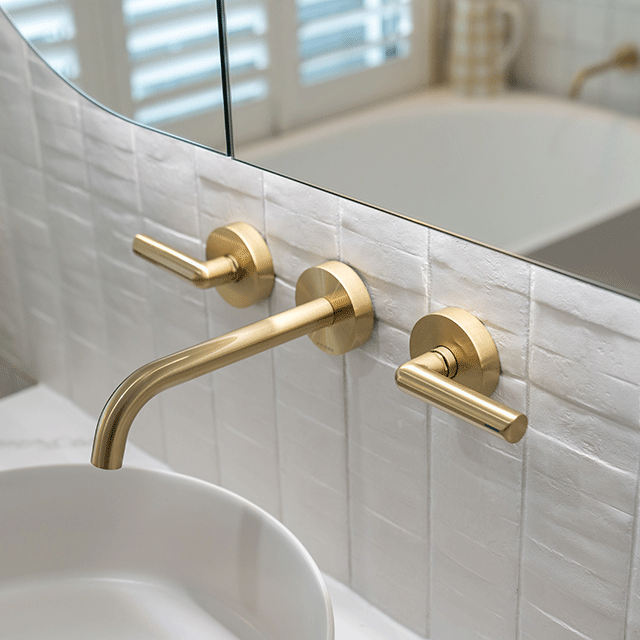 Phoenix Vivid Slimline Plus brushed gold wall top assemblies with lever handles and wall spout over a basin sink