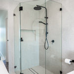 Phoenix Vivid Slimline matte black wall shower mixer in a modern shower room with glass screen