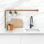 Phoenix Vivid Slimline matte black gooseneck sink mixer with side lever on a white kitchen benchtop