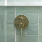 Phoenix Vivid Slimline brushed gold shower/bath diverter mixer with round wall plate and slim lever on green tiles
