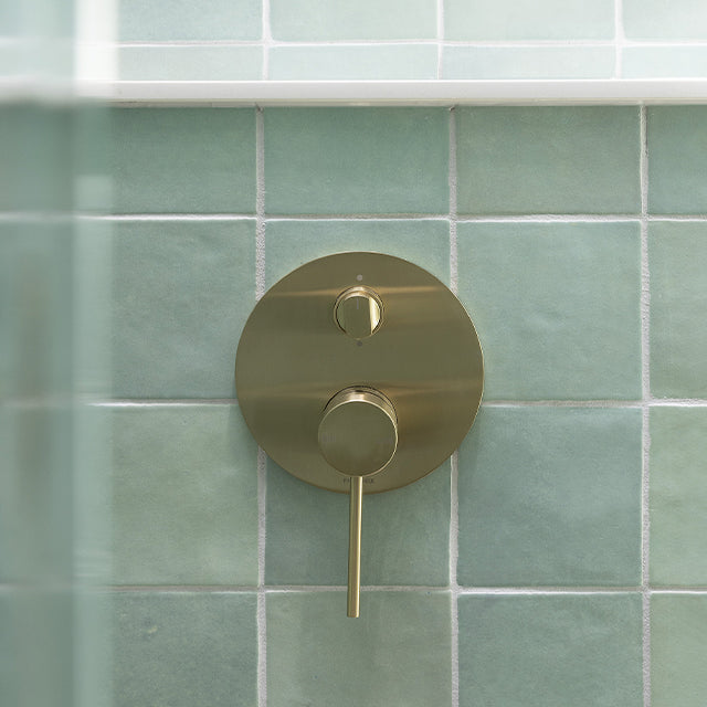 Phoenix Vivid Slimline brushed gold shower/bath diverter mixer with round wall plate and slim lever on green tiles