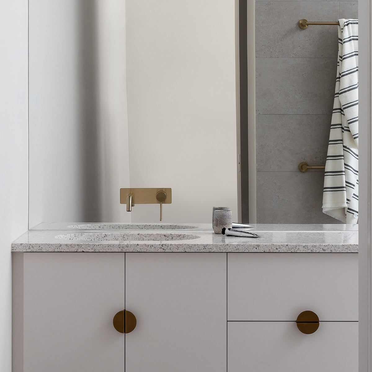 Phoenix Vivid Slimline wall basin mixer in brushed gold over a terrazzo vanity in a modern bathroom