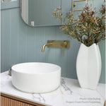 Phoenix Vivid Slimline brushed gold wall basin mixer over a white vessel basin in a styled bathroom vanity setting